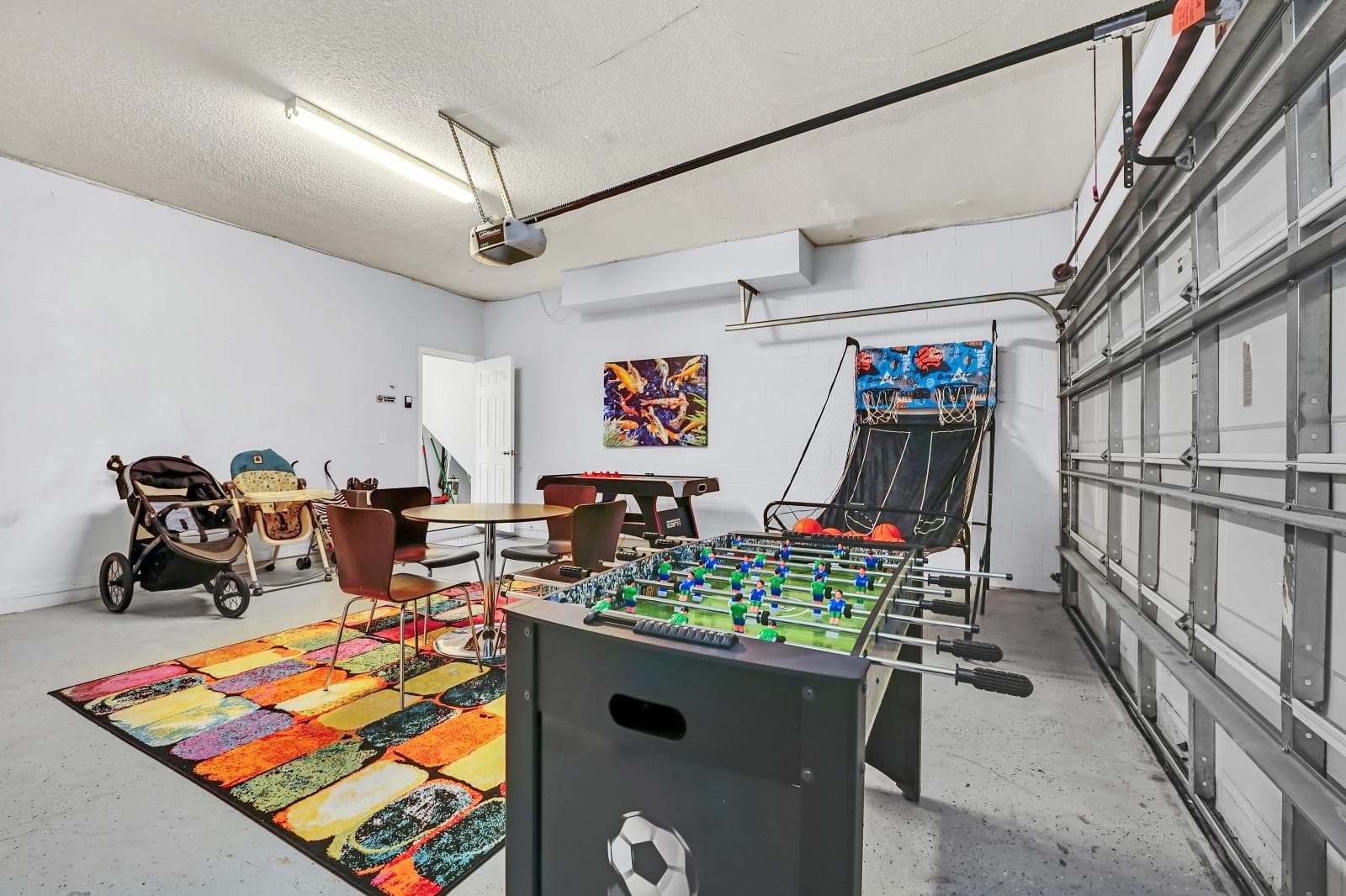 The games room in the converted garage: a foosball table, an air hockey table and an arcade basketball machine on a bright rug