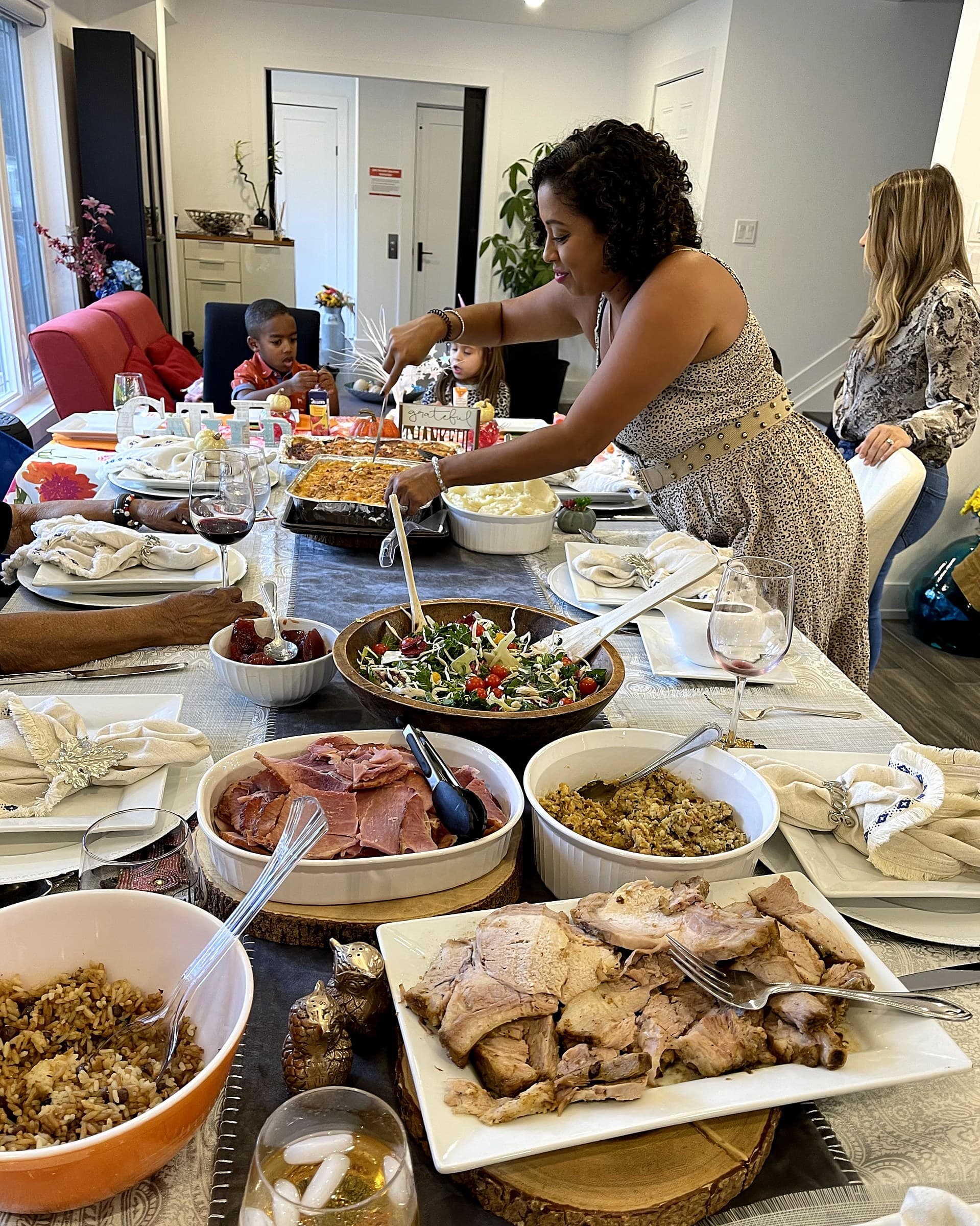A family meal being served at the long dining table, dishes covering the length of it, with a child seated further along