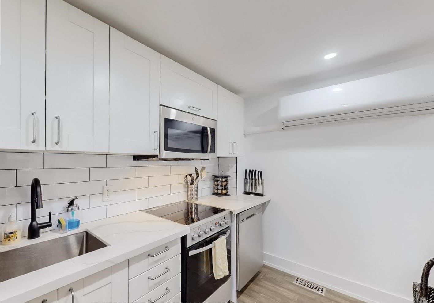 The suite’s own kitchen: white cabinetry, a full range and oven, microwave, dishwasher and sink under a subway-tiled wall