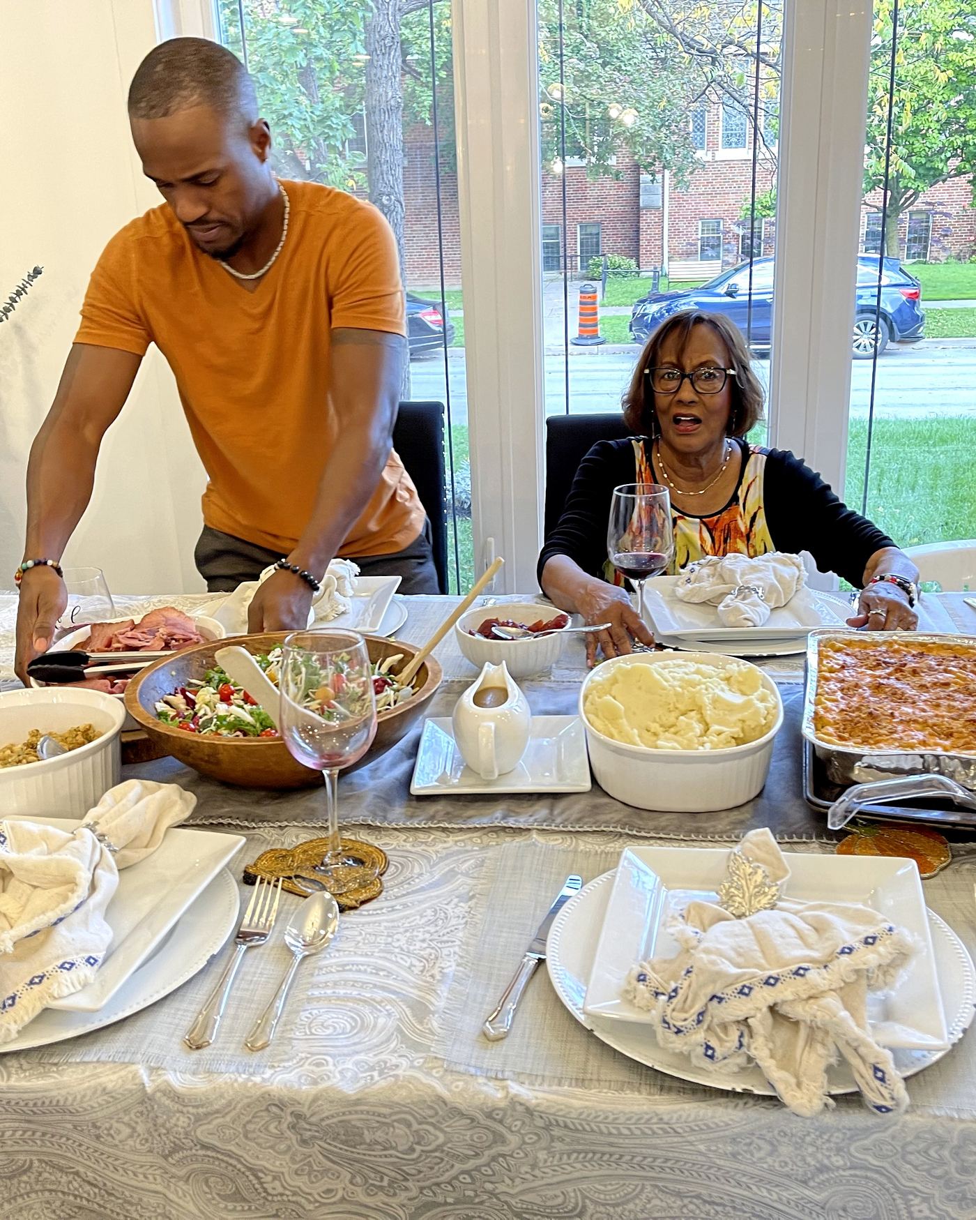 Three generations of a family gathered around the long dining table at Gatherwell in Etobicoke, Toronto, with candles lit and the garden windows behind them